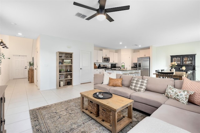 tiled living room with ceiling fan and sink