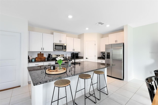 kitchen featuring a kitchen island with sink, sink, stainless steel appliances, and white cabinets