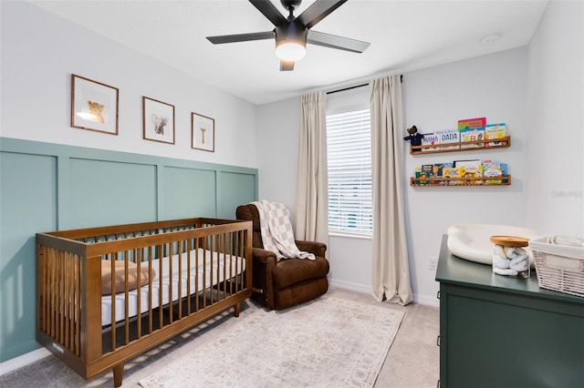 carpeted bedroom featuring a crib and ceiling fan