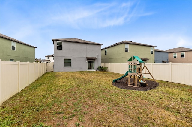 back of property with a yard and a playground