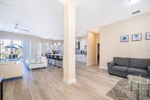 living room featuring ceiling fan, sink, and light hardwood / wood-style floors