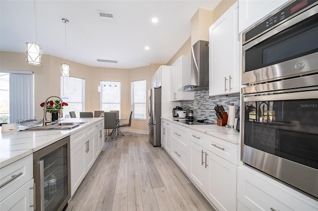 kitchen featuring white cabinetry, wall chimney range hood, and wine cooler