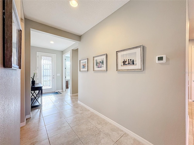 corridor featuring light tile patterned flooring and a textured ceiling