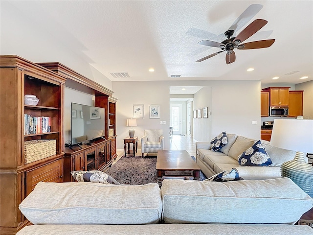 living room featuring ceiling fan and a textured ceiling