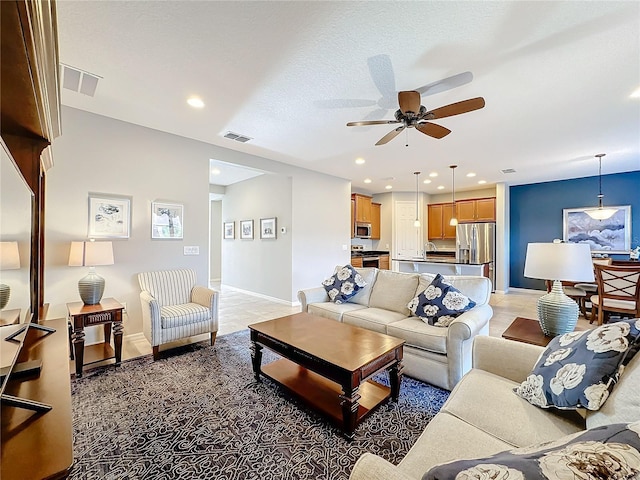 living room with ceiling fan, sink, and a textured ceiling