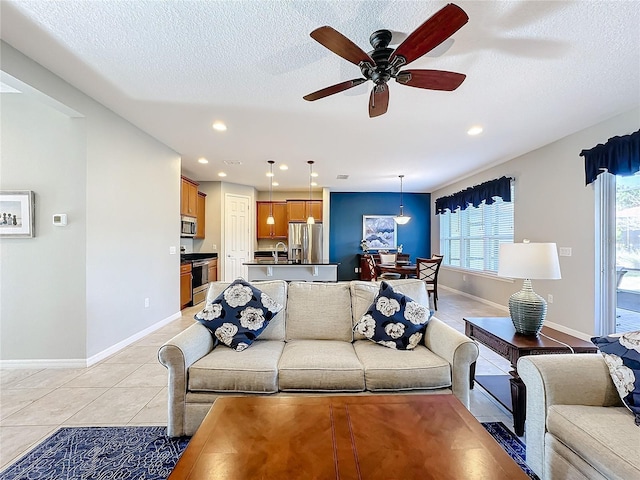 tiled living room with sink, a textured ceiling, and ceiling fan