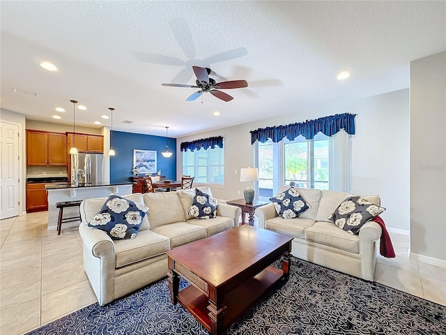 living room with light tile patterned flooring, ceiling fan, and a textured ceiling