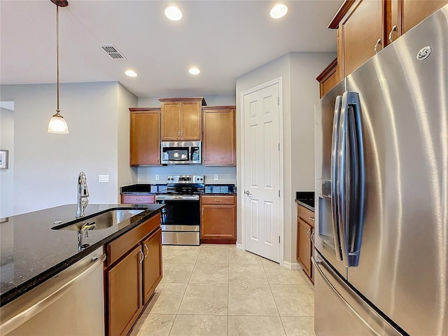 kitchen featuring sink, light tile patterned floors, dark stone countertops, pendant lighting, and stainless steel appliances