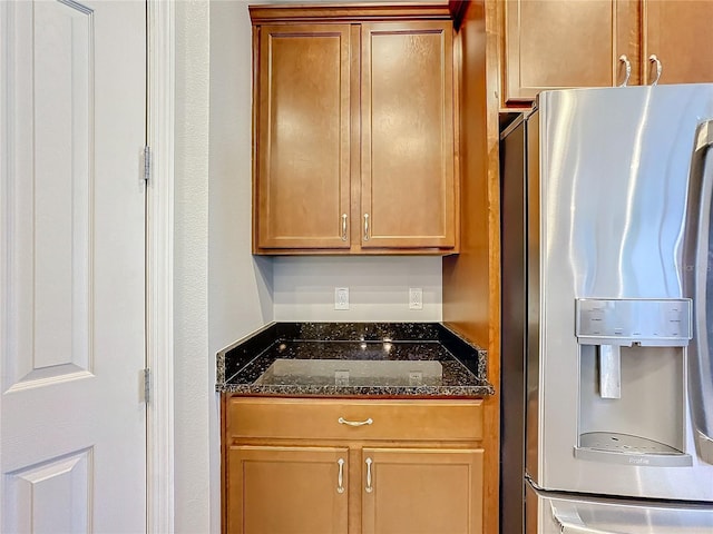 kitchen with dark stone countertops and stainless steel fridge with ice dispenser