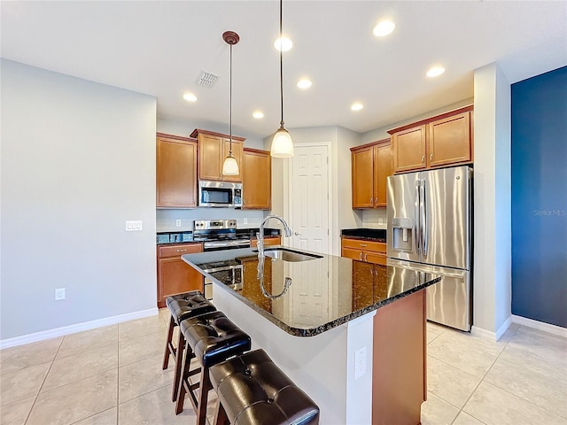 kitchen featuring appliances with stainless steel finishes, sink, a kitchen breakfast bar, hanging light fixtures, and a kitchen island with sink