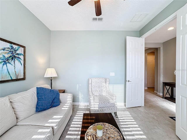 living room with a textured ceiling and ceiling fan