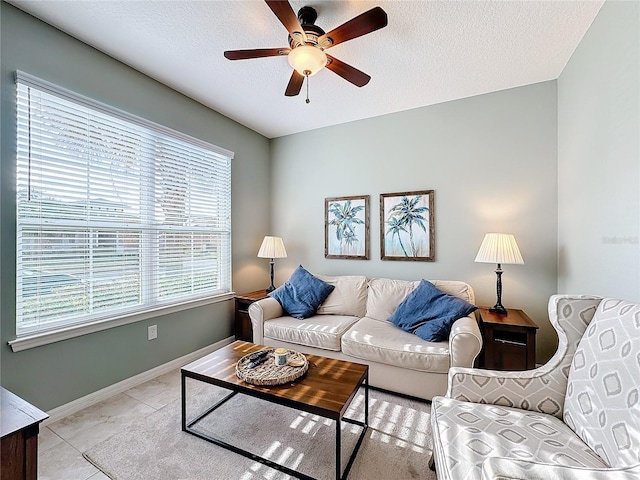 living room with light tile patterned flooring, ceiling fan, and a textured ceiling