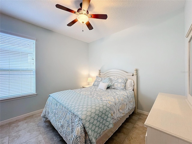 bedroom featuring light tile patterned flooring, ceiling fan, and a textured ceiling