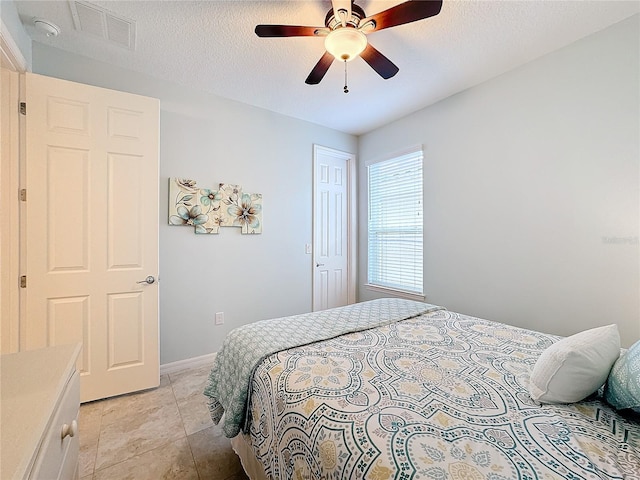 bedroom with ceiling fan and a textured ceiling