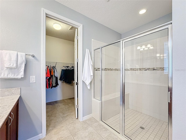 bathroom featuring vanity, tile patterned floors, a textured ceiling, and walk in shower