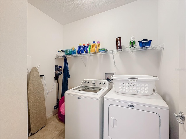 laundry area featuring washer and dryer, light tile patterned floors, and a textured ceiling