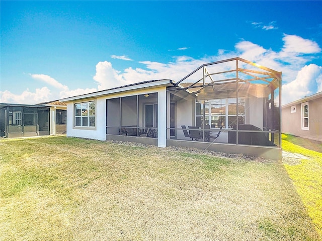 rear view of house with a patio area, a lawn, and glass enclosure