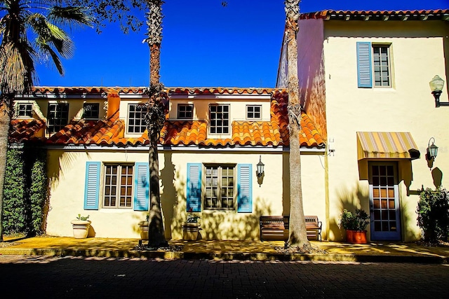 rear view of property featuring a tile roof and stucco siding