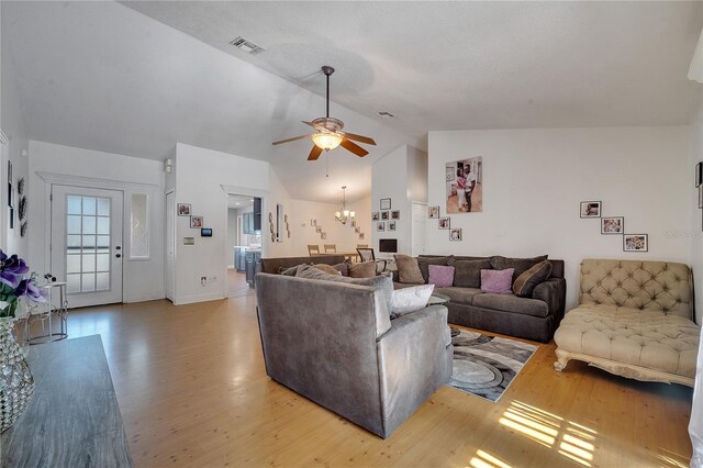 2417 Liela Lee Ct, Ocoee, FL 34761 - living room with ceiling fan with notable chandelier, vaulted ceiling, and light hardwood / wood-style flooring