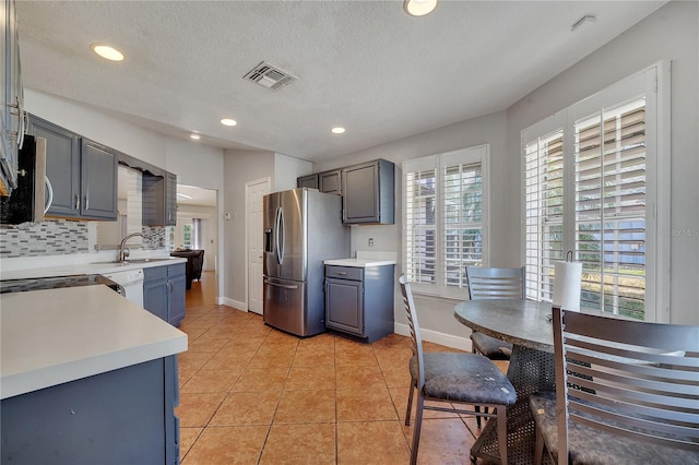 2417 Liela Lee Ct, Ocoee, FL 34761 - kitchen featuring appliances with stainless steel finishes, sink, backsplash, light tile patterned floors, and a textured ceiling