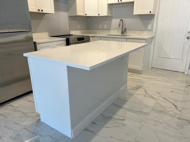 kitchen with white cabinetry, appliances with stainless steel finishes, a center island, and sink