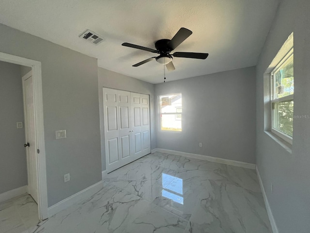 unfurnished bedroom featuring ceiling fan, a textured ceiling, and a closet