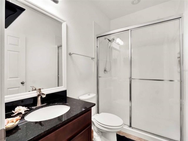 bathroom with toilet, a shower stall, and vanity