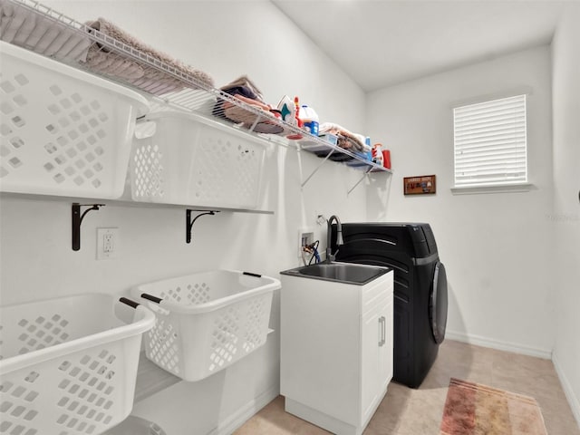 clothes washing area with washer and clothes dryer, baseboards, and light tile patterned floors