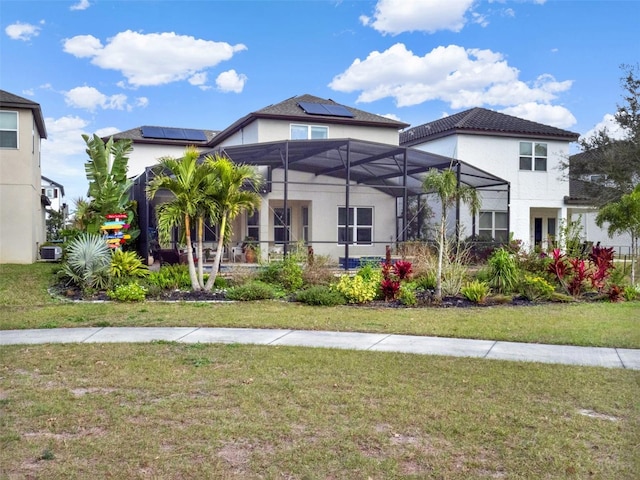 view of front of home featuring a lanai, roof mounted solar panels, a front lawn, and stucco siding