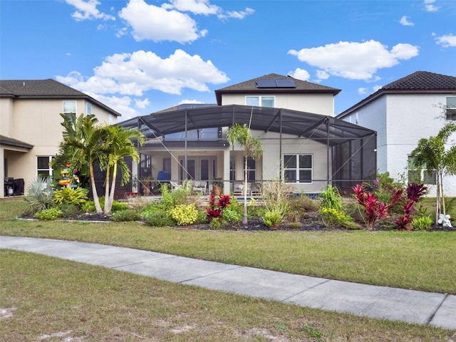 view of front of house with a front yard, glass enclosure, and stucco siding