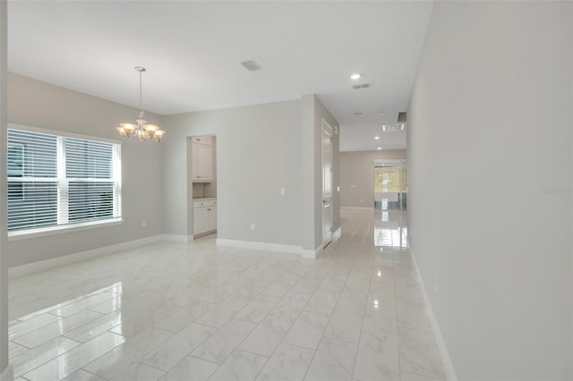 spare room featuring a wealth of natural light and an inviting chandelier