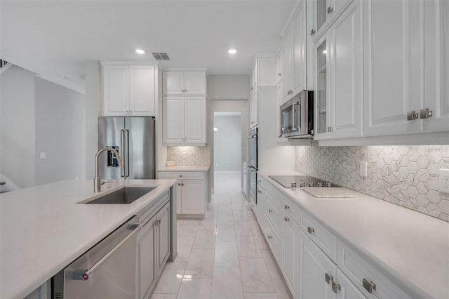 kitchen featuring appliances with stainless steel finishes, sink, decorative backsplash, and white cabinets