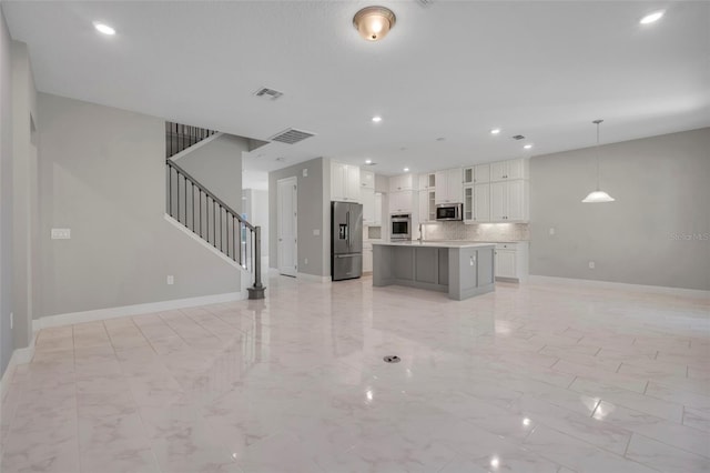 kitchen with a kitchen island, appliances with stainless steel finishes, decorative light fixtures, tasteful backsplash, and white cabinets