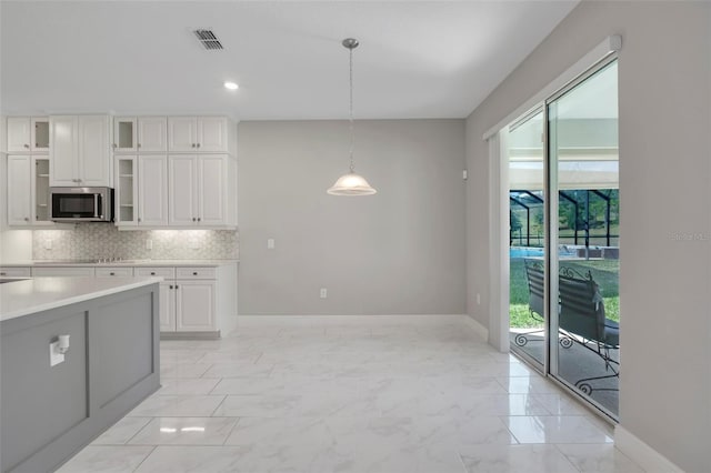 kitchen with white cabinetry, hanging light fixtures, and tasteful backsplash