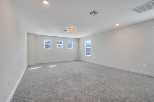 carpeted empty room with a textured ceiling