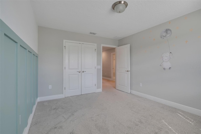 unfurnished bedroom with light colored carpet and a textured ceiling