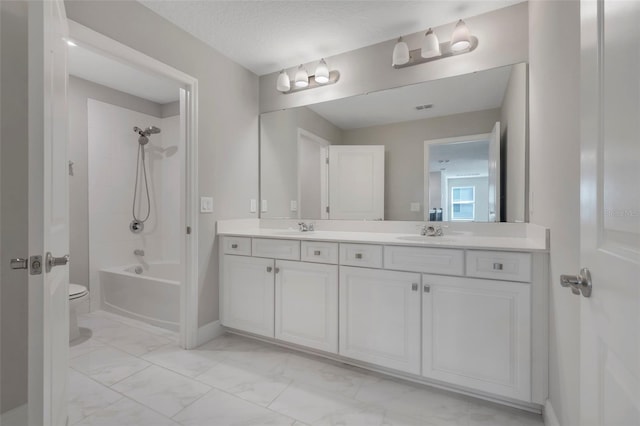 full bathroom with tiled shower / bath, vanity, a textured ceiling, and toilet