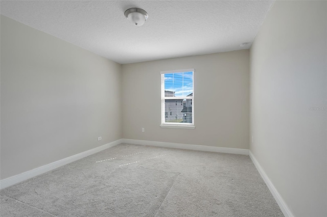 spare room featuring light carpet and a textured ceiling