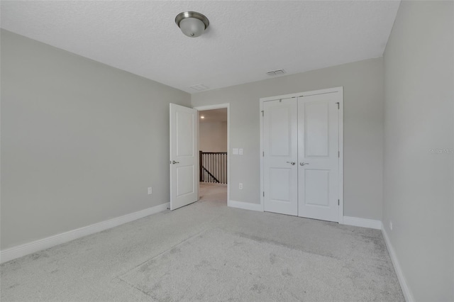 unfurnished bedroom featuring light colored carpet, a closet, and a textured ceiling