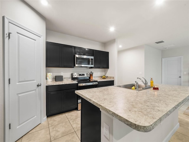 kitchen with appliances with stainless steel finishes, sink, an island with sink, and light tile patterned floors