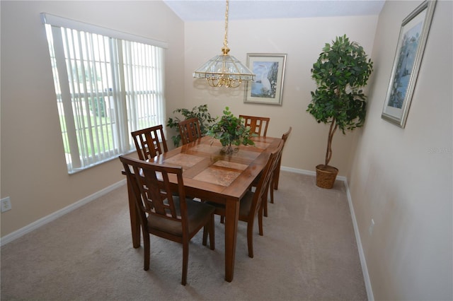 carpeted dining area featuring lofted ceiling and a notable chandelier