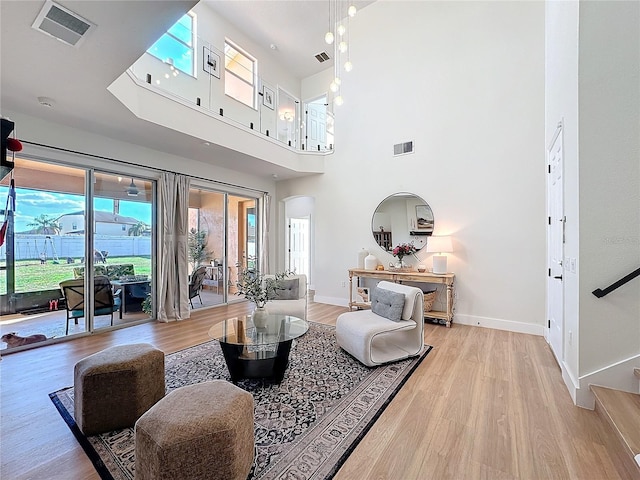 living room with a towering ceiling and light hardwood / wood-style floors