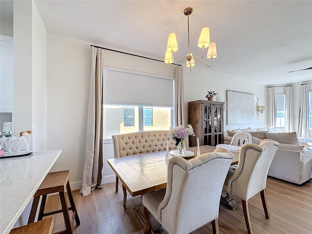 dining space featuring hardwood / wood-style flooring, a textured ceiling, and a notable chandelier