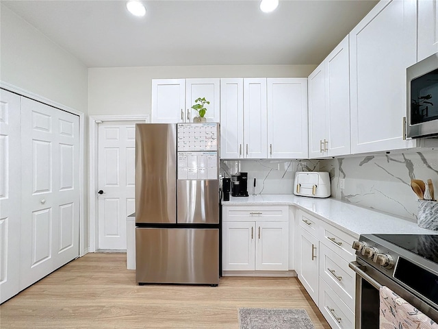 kitchen with appliances with stainless steel finishes, light wood-type flooring, and white cabinets