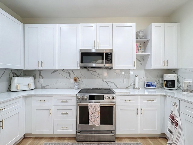 kitchen with appliances with stainless steel finishes, light hardwood / wood-style flooring, and white cabinets