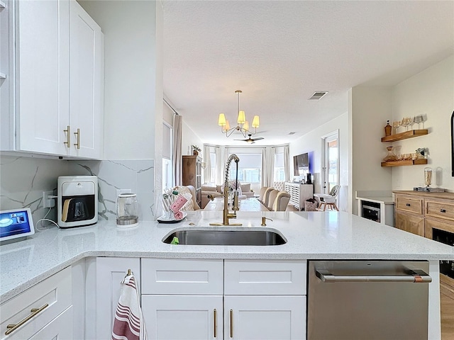 kitchen with sink, stainless steel dishwasher, pendant lighting, light stone countertops, and white cabinets