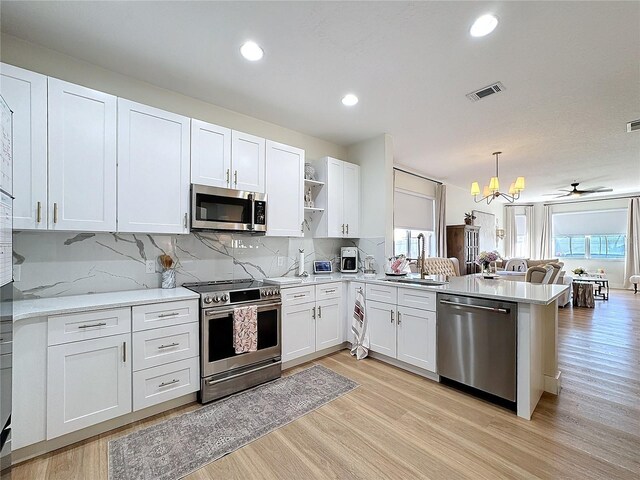 kitchen featuring hanging light fixtures, white cabinetry, appliances with stainless steel finishes, and sink