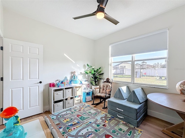 game room featuring a textured ceiling, light hardwood / wood-style floors, and ceiling fan