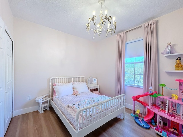 bedroom with hardwood / wood-style flooring, a textured ceiling, and a chandelier