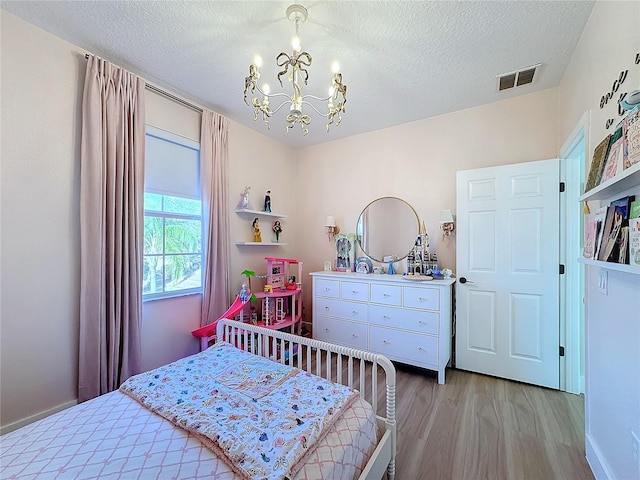 bedroom with a chandelier, a textured ceiling, and light wood-type flooring